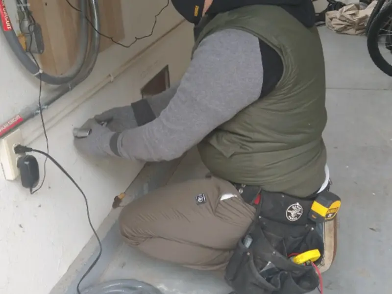 Electrician performing outlet wiring in a Cato garage